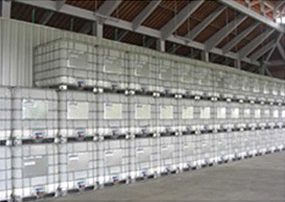 Stacked industrial IBC containers storing organic aloe vera liquid.